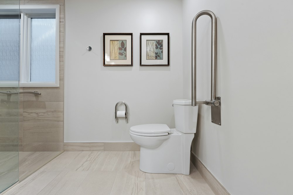 Baño adaptado con barra de apoyo abatible junto al inodoro y ducha a ras de suelo